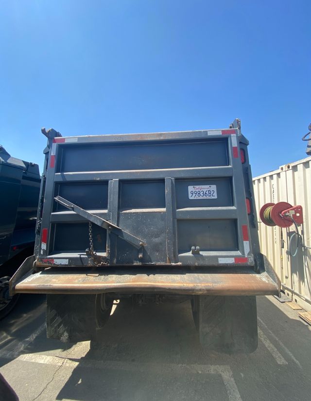 Rear view of a blue Peterbilt dump truck bed with a tailgate latch and a small Oregon or California license plate mounted on the back.