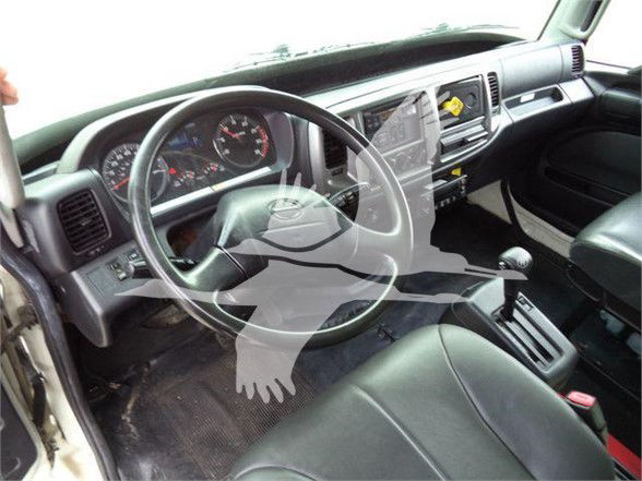 Truck cab interior showing steering wheel, dashboard gauges, gear selector, and front seats.