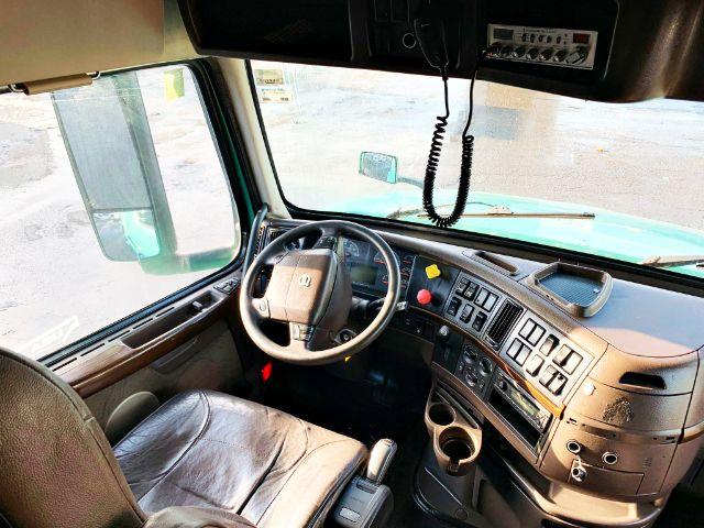 Truck cab interior with steering wheel, dashboard, and control panel. Visible text on dashboard and controls includes generic labels but no legible serials.