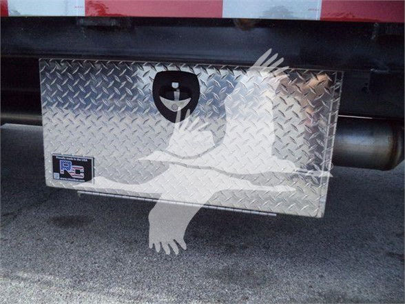 Aluminum diamond plate toolbox mounted under a Silverado 6500HD rear with a circular key handle and small RCI logo plate.