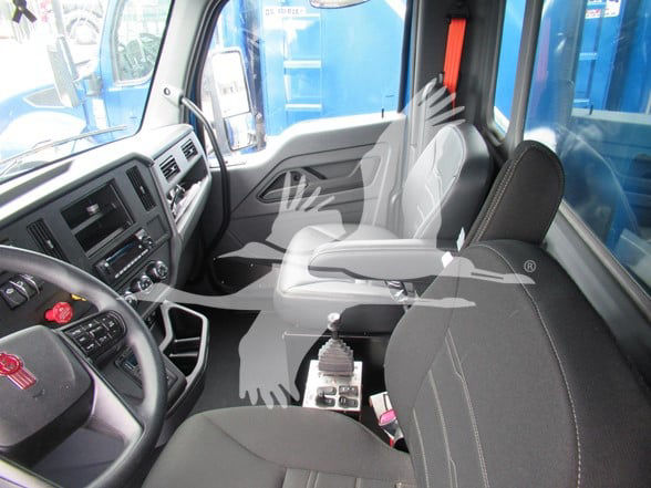 Interior of a 2025 Kenworth T380 cab showing steering wheel, dashboard, driver seat, passenger seat, gear shifter, center console.