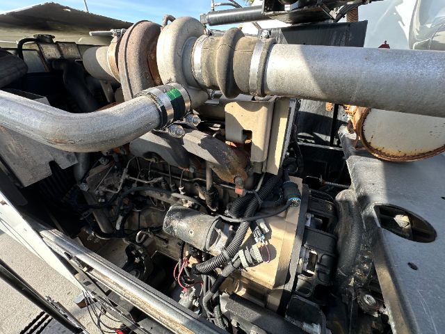 Industrial vacuum truck engine bay showing large turbocharger and air piping with various hoses and electrical connectors.