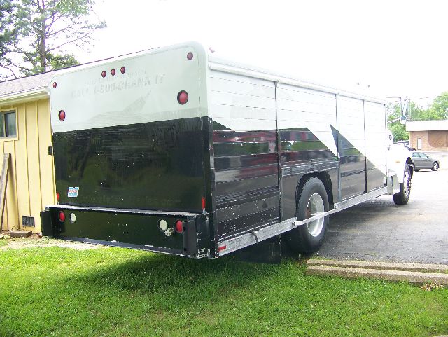Peterbilt 335 box truck seen from rear left side, long rectangular cargo box, black lower body with white upper, rear doors closed, single rear wheel visible.