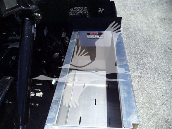 Tow truck equipment bin with metal shiny interior and warning label; image shows a metal tray with side walls and a sticker near top.