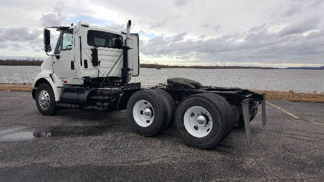 Side view of a white 2007 International 8600 conventional daycab truck chassis with dual rear axles and fuel tanks, empty fifth wheel area, overcast sky.