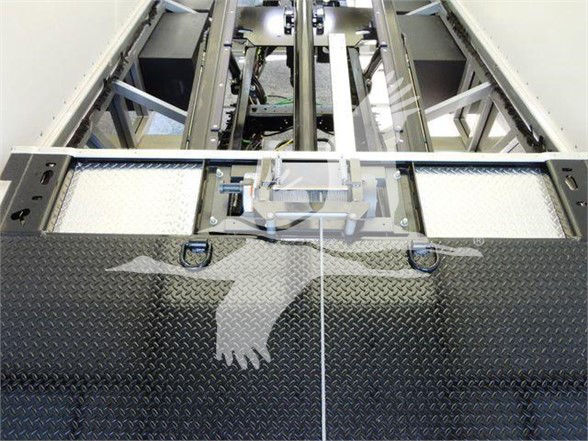 Truck bed interior showing diamond plate surface and mounting rails with latching mechanisms.