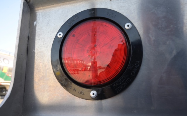 Vacuum trailer rear showing circular red taillight housing with metal surface.