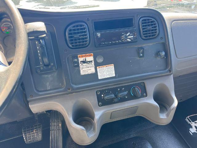 Dashboard area of a Freightliner M2 106 truck interior with center console, gauges, vents, and control switches visible.