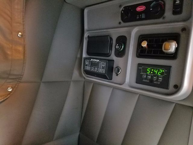 Peterbilt 389 cab interior panel with various controls, a digital clock displaying 5:42, and switches.