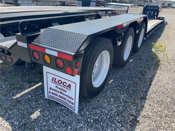 Trailer rear left side showing dual rear axles, diamond plate deck and ILOCA sign.