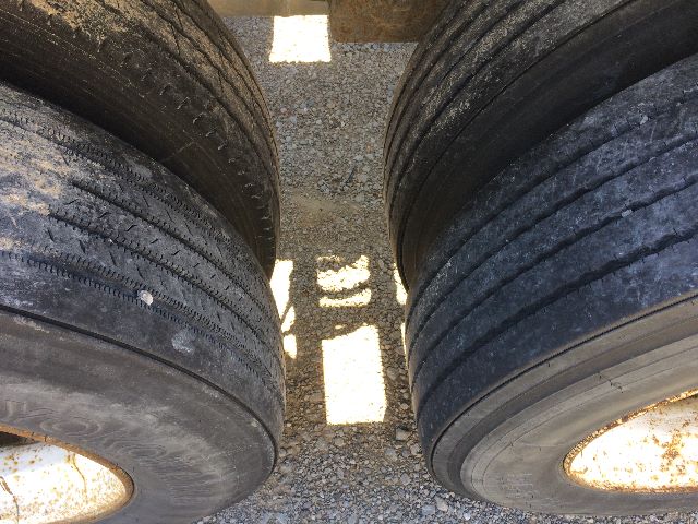 Pneumatic dry bulk trailer tandem wheels showing worn tread on tires and wheel hubs.