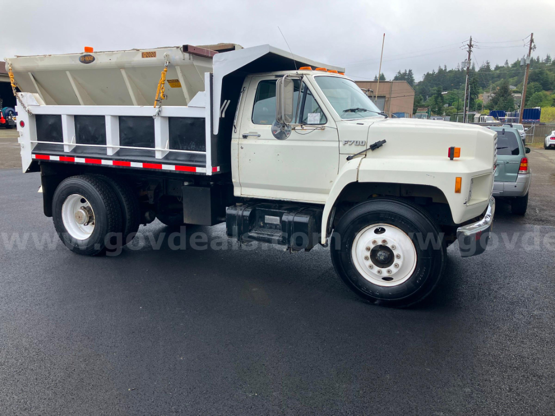 Ford F7000 dump truck side view showing dump bed and white cab with chrome mirrors and black step, VIN 1FDXK74N0HVA15888