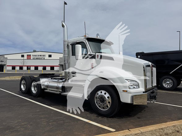 Kenworth T880 truck cab and chassis in white, with long twin rear axles and chrome exhaust stacks visible in a parking lot.