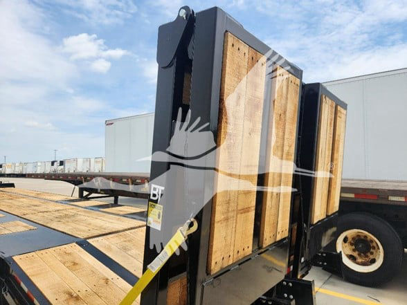 Flatbed trailer with wooden side panels and vertical loading ramp.