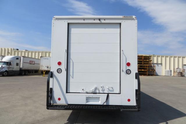 Rear view of a 2015 Ford F59 box truck with a roll-up rear door, two red taillights, and a black bumper.
