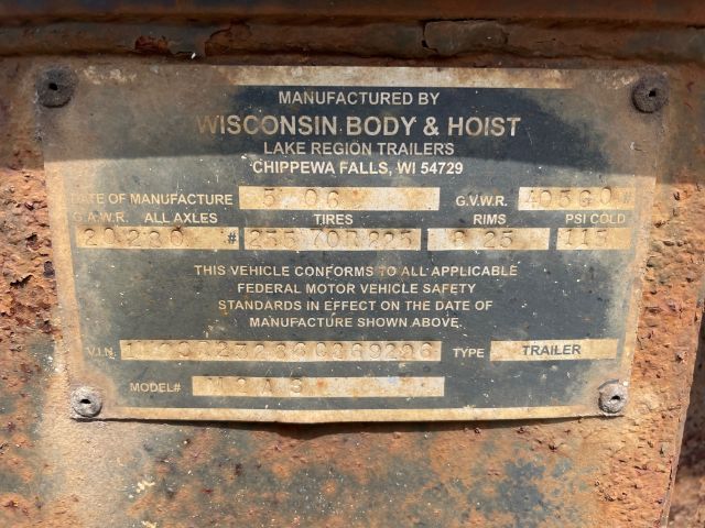 Manufactured by Wisconsin Body & Hoist plate on trailer with serial numbers and GVWR details; text worn but legible: Manufacturer info, GVWR, GAWR, tires, rims, psi cold, VIN, model, trailer type.