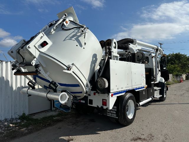 Truck-mounted vacuum with large rotating drum and hose reel, white Freightliner 108SD body, side compartments, and rear-mounted vacuum apparatus