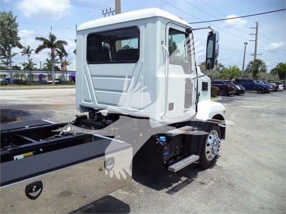 Truck cab side and rear showing empty chassis for a 2024 Mack MD6; no visible fluid labels or text on the cab panels.