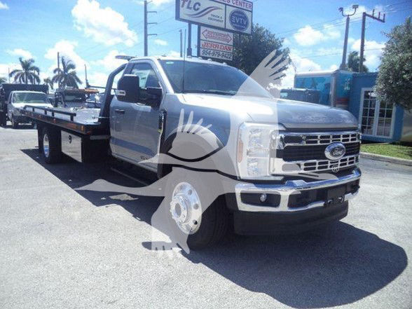 Truck in a tow configuration with a flatbed, front grille and Ford emblem visible; generic dealership lot in background.
