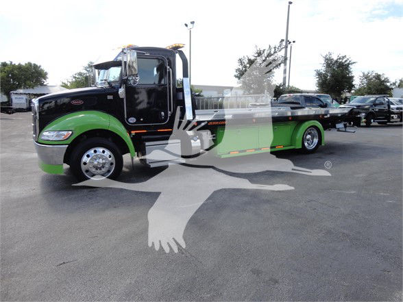 Peterbilt 337 tow truck in black and green livery with chrome wheels, side profile view.