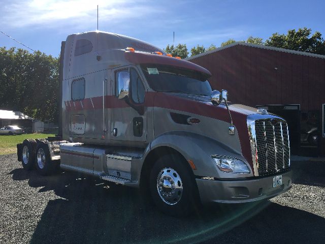 Peterbilt 578 conventional sleeper tractor in silver with maroon stripe, front grille, chrome bumper, and dual rear axles. visible side fuel tanks and mirrors.