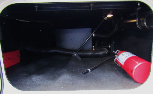 Kenworth T680 engine bay compartment with a red fire extinguisher and wiring harness visible.