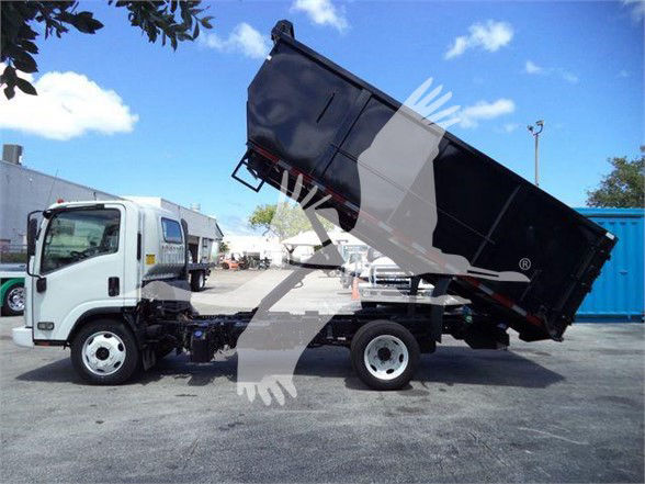 Isuzu NRR dump truck with dumping bed raised, white cab, black dump body, in a lot.