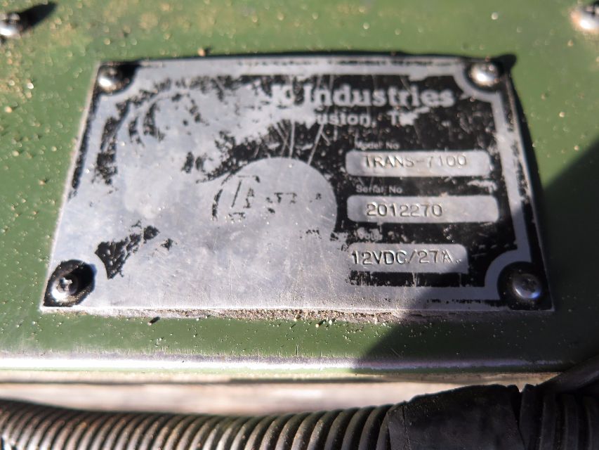 Conspicuously weathered metal nameplate on green truck surface with serial numbers and text, screws at corners.