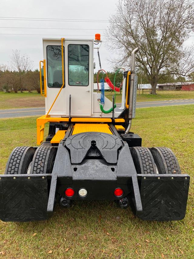 Kalmar Ottawa yard truck rear view showing cabin with yellow railing, black chassis, dual rear axles, and fluid/maintenance hoses near the cab.
