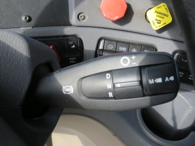 Cab interior of a 2016 Freightliner Cascadia Evolution showing gear selector stalk with D N R positions and control buttons, dashboard switches, and yellow parking brake cap.