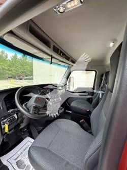 Kenworth T880 truck interior showing steering wheel, dashboard, and front seats; plastic covers on the driver controls; overhead storage and sun visor.