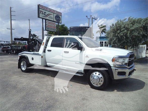 Ram 5500 tow truck white crew cab with utility bed, front chrome bumper, large mirrors, in a dealership lot.