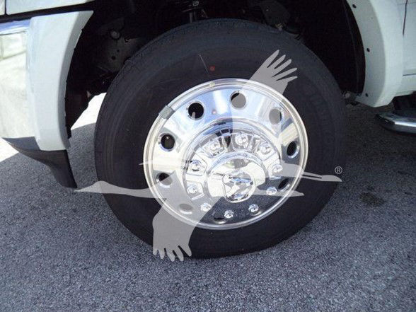 Wheel close-up on a Ram 5500 tow truck showing chrome hubcap and tire with fender in view.