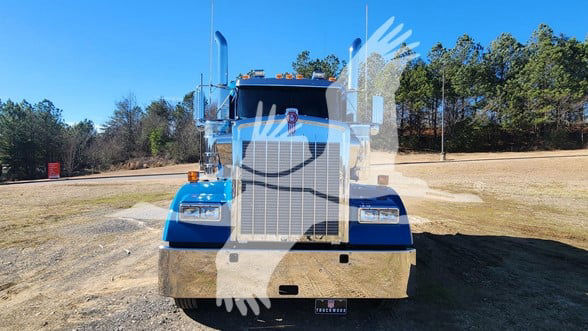 Kenworth W900L conventional sleeper truck front view showing large grille and bumper, blue paint, hood, headlights, and windshield.
