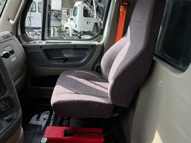 Truck cab interior showing driver's seat and door panel of a Freightliner Cascadia 125 interior.