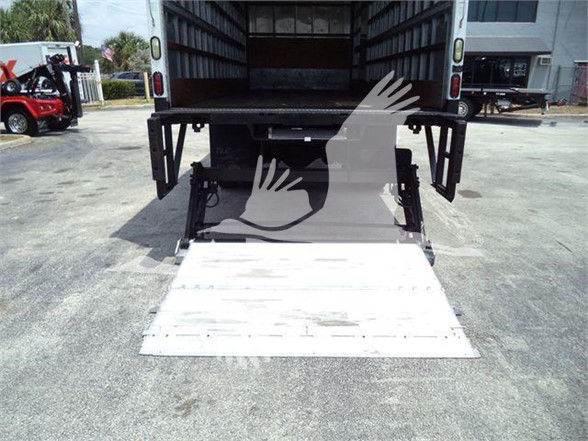 Rear view of a 2023 Mack MD7 box truck with a lowered aluminum ramp at the cargo area.