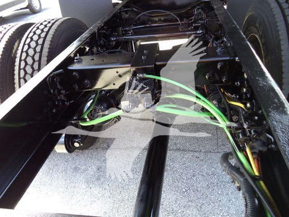 Underframe of a 2019 International DURASTAR 4300 truck showing chassis, axles, and green hydraulic/air lines with wiring harnesses.