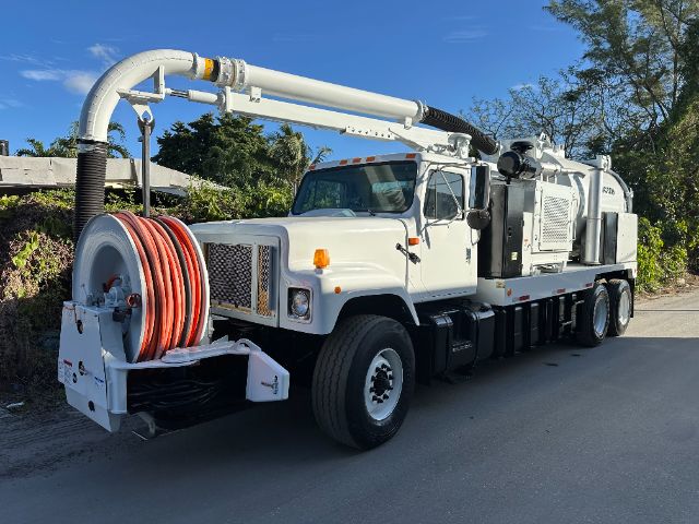 International truck vacuum unit with large rear hose reel and long articulating boom pump assembly.