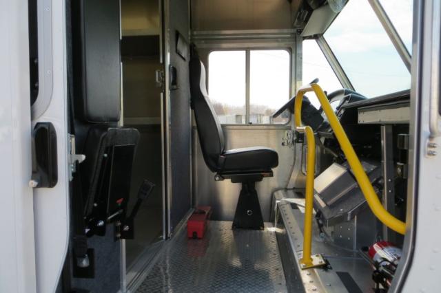 Ford F59 step van interior with driver seat and control area, aluminum flooring, yellow handrails, and entry area.