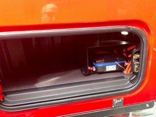Western Star 4900 engine bay showing battery and wiring in side storage compartment.