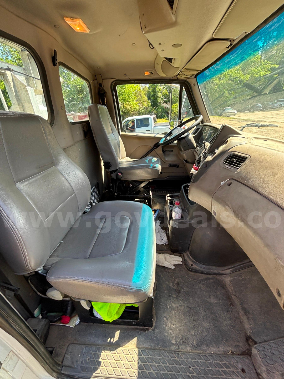 Cab and chassis interior of 2009 Sterling LT9500 showing driver and passenger seats, steering wheel, dashboard, and worn floor mat.