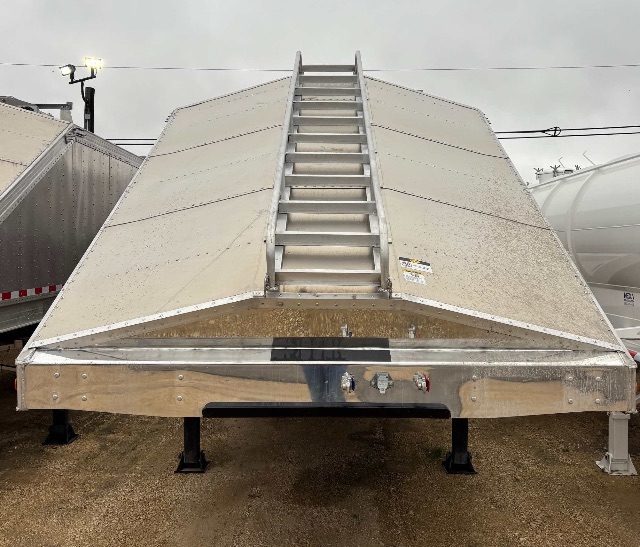 Aluminum sand/grain hopper trailer viewed from front with a central ladder leading to top, diamond plate trim, and leveling legs.