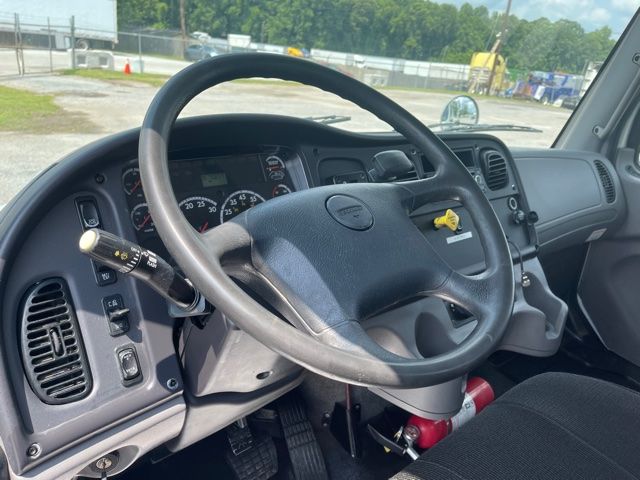 Freightliner M2 dash and steering wheel interior showing gauges and control stalks.