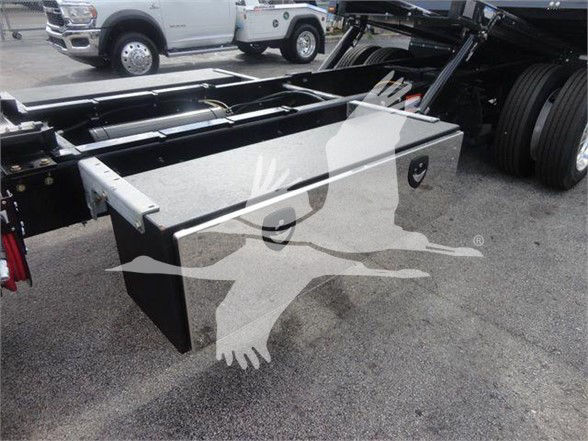 Truck chassis with large aluminum tool/storage box mounted on frame, side view, part of International MV cab and chassis in background.
