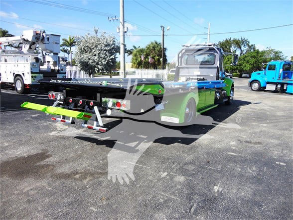 Peterbilt 337 tow truck chassis with green and black color, rear equipment, parked lot.