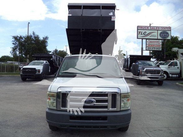 Front view of a white 2011 Ford E450 dump truck with a raised dump bed in a dealership lot.