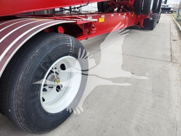 Trailer wheel and red container chassis showing front wheel and side profile.