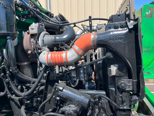 Trucks engine bay showing large turbocharger piping, orange flexible hose, and cooling system components in a Peterbilt 348 engine bay.