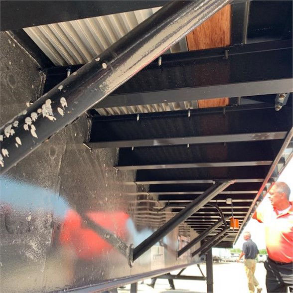 Underframe of a 2024 Vanguard 48ft steel flatbed trailer showing support beams and structural members.