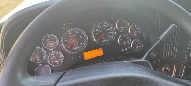 Dashboard of a truck showing multiple gauges and an orange rectangular sticker/label at center. Steering wheel dominates foreground.
